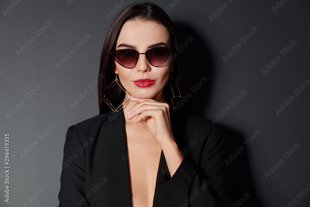Beautiful woman wearing jacket and sunglasses on black background Beautiful woman wearing jacket and sunglasses on black background