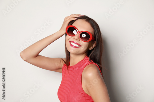 Beautiful woman in stylish sunglasses on light background