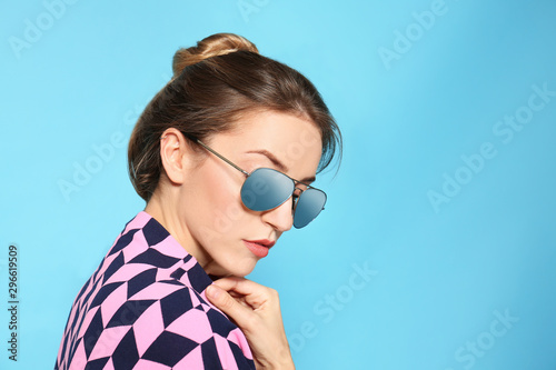 Young woman wearing stylish sunglasses on blue background. Space for text