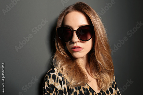 Young woman wearing stylish sunglasses on dark grey background