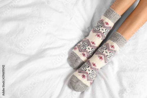 Woman wearing knitted socks on white fabric, top view with space for text. Warm clothes