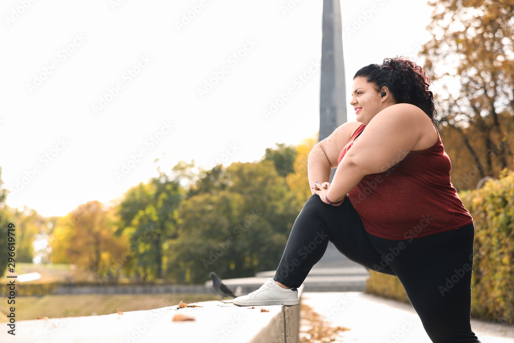 Beautiful overweight woman doing sport exercises in park - obrazy, fototapety, plakaty 
