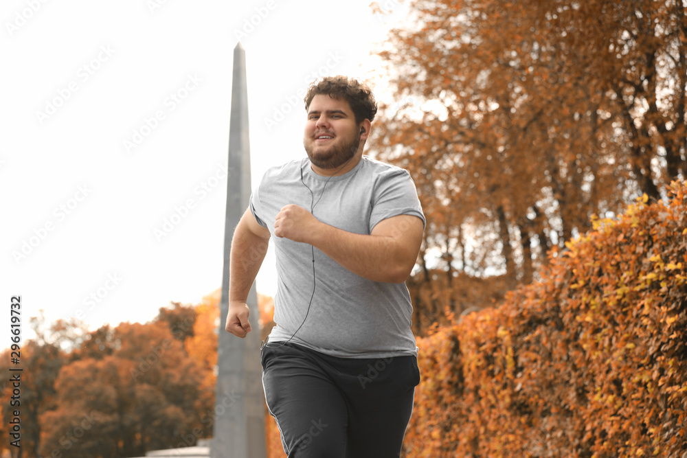 © New Africa - Young overweight man running in park. Fitness lifestyle
