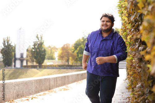 Young overweight man running in park. Fitness lifestyle photo