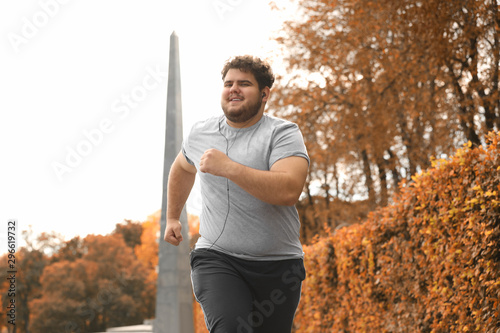 Young overweight man running in park. Fitness lifestyle
