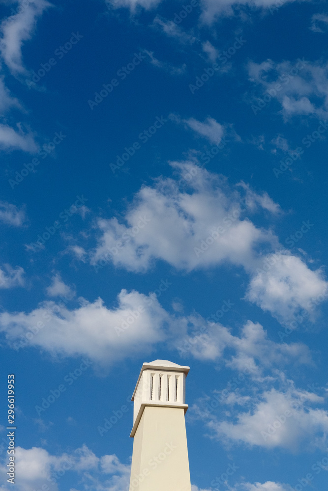 Cloudy blue sky in Algarve with a chimney.