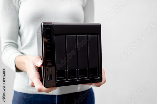 female holds small nas backup server. data backup and security concept. photo