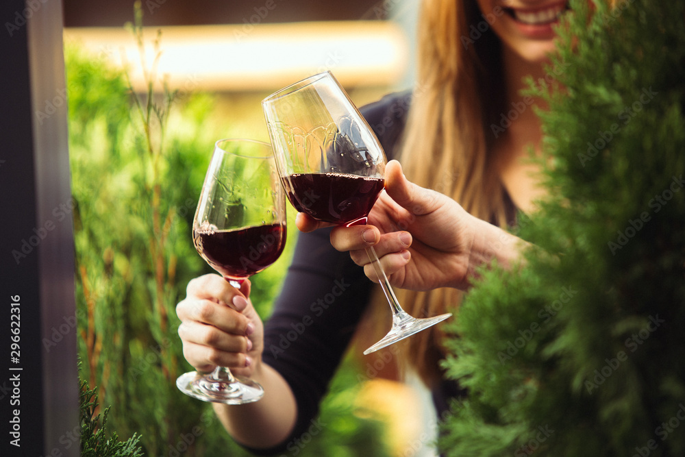 People clinking glasses with wine on the summer terrace of cafe or restaurant. Happy cheerful friends celebrate summer or autumn fest. Close up shot of human hands, lifestyle. People clinking glasses with wine on the summer terrace of cafe or restaurant. Happy cheerful friends celebrate summer or autumn fest. Close up shot of human hands, lifestyle.