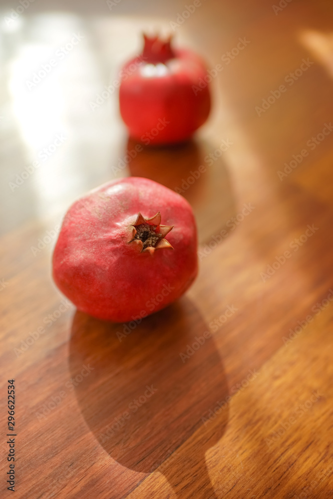 Two whole ripe pomegranate on the brown wooden sunny table. Two whole ripe pomegranate on the brown wooden sunny table.