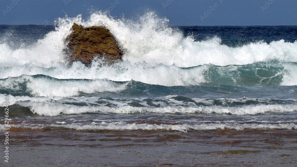 Fototapeta premium Powerful waves crashing on a large rock in sea. Taken at Sango Sands, Durness in the summer. Part of the North Coast 500 tourist route.