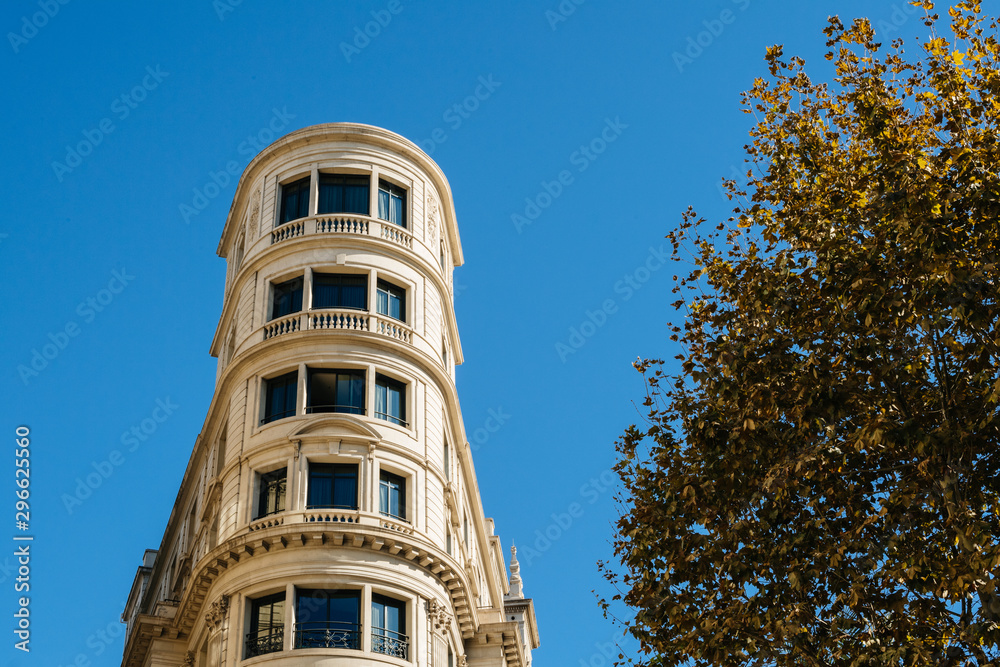 Luxury apartment building against clear blue sky in central Barcelona with tree canopy and large copy space