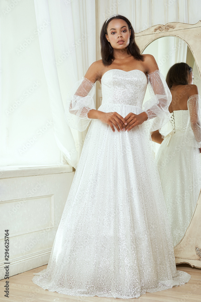 Fototapeta premium Dark-skinned bride posing in a wedding dress
