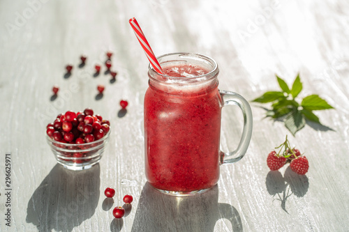 Fresh organic red smoothie in glass mug on white table, close up. Refreshing summer fruit drink. The concept of healthy eating. Cranberry and raspberry smoothie