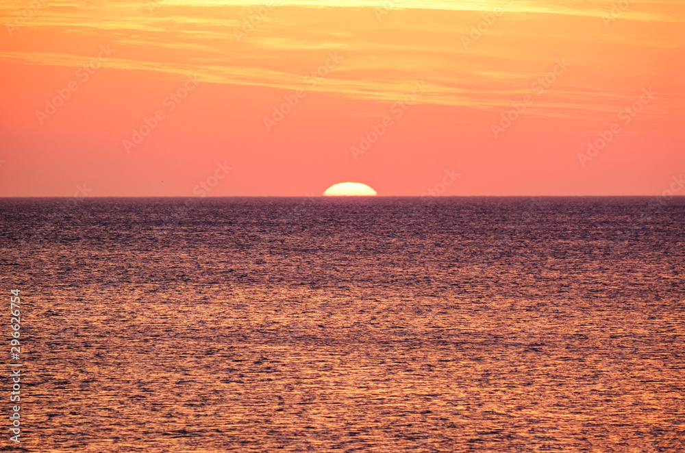 Faszinierende Abendstimmung: Traumhafter gelb-roter Sonnenuntergang Ã¼ber dem Meer mit einer fast untergegangenen, verschwommenen Sonne