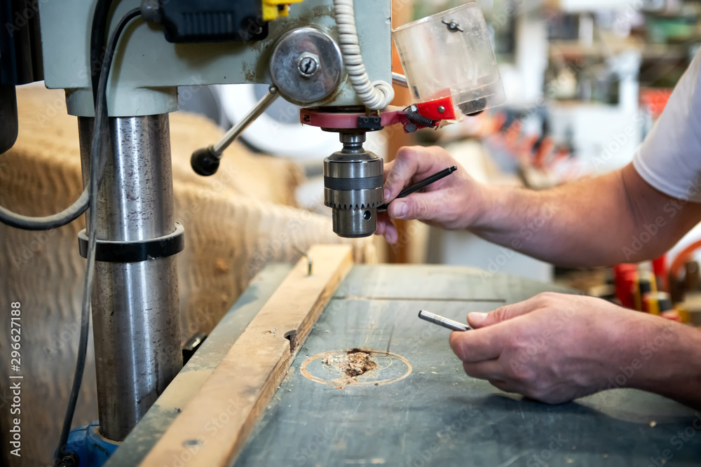 Carpenter changing the bit on a vertical drill Carpenter changing the bit on a vertical drill