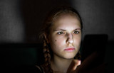 portrait of young teenager redhead girl with long hair with smartphone in dark room