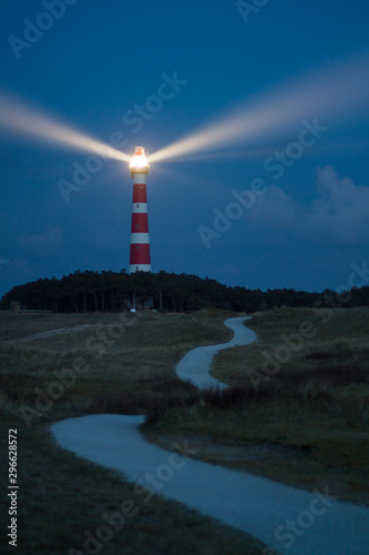 lighthouse of Ameland at night with light beaming across the deep blue sky photo