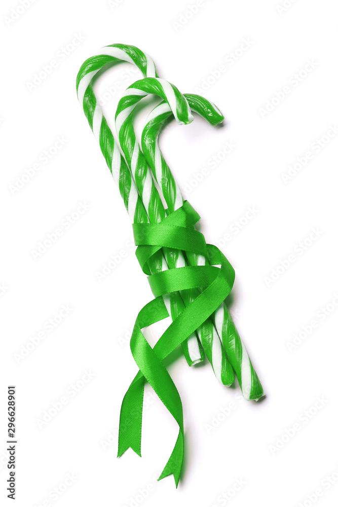 Tasty red candy cane with bow on white background. Festive treat Tasty red candy cane with bow on white background. Festive treat