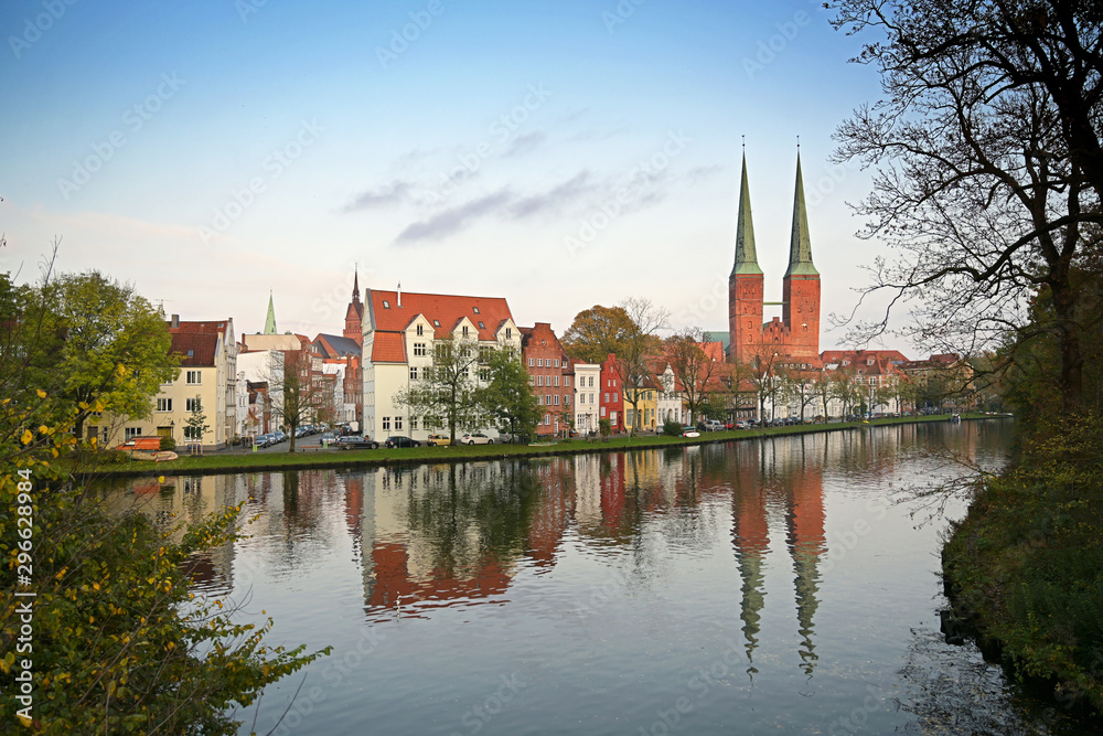 Obraz premium Cityscape of the historic old town of Luebeck at the Malerwinkel, or painter's corner, two towers of the cathedral, in German Dom, reflection in f the river Trave, blue sky, copy space