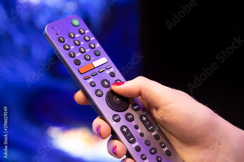 female hand holds a smart TV remote control with microphone and voice control. background in blur. soft focus