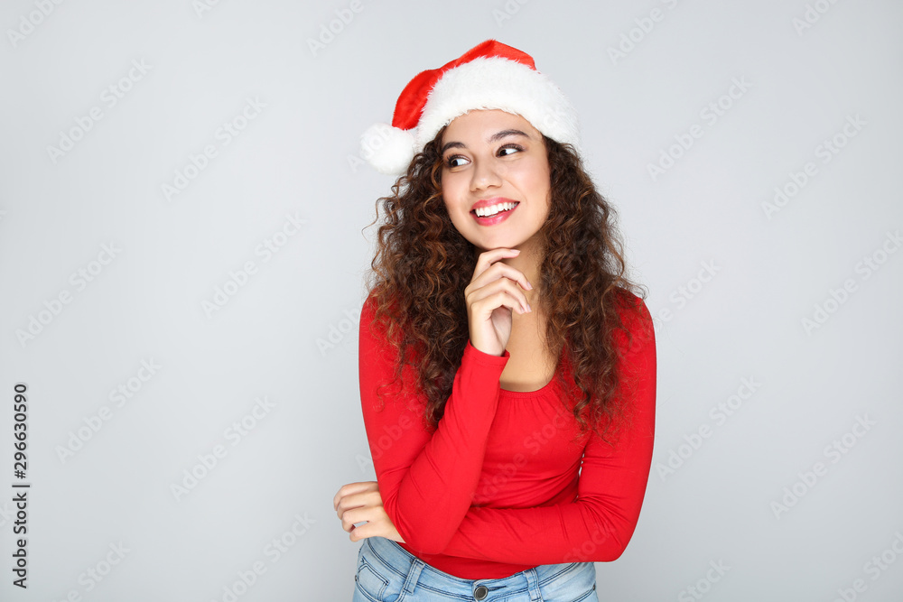 Beautiful american woman in santa hat on grey background Beautiful american woman in santa hat on grey background