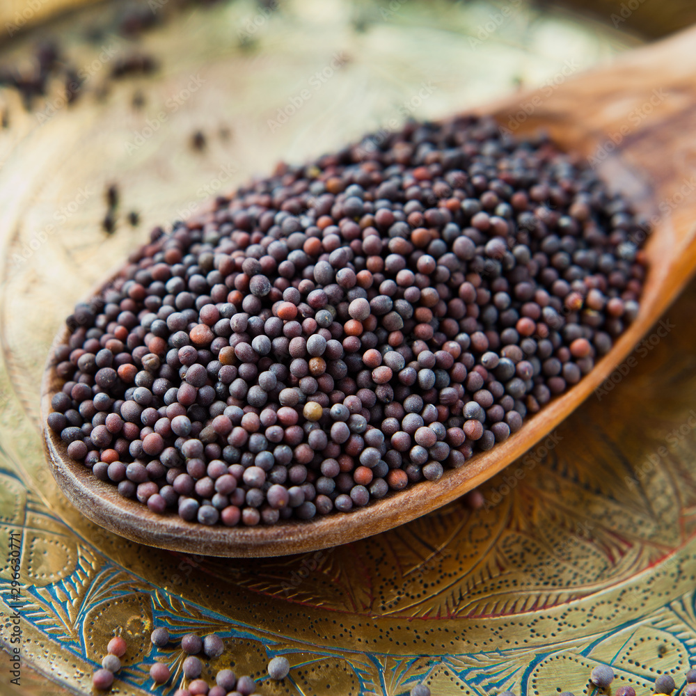 Black Mustard Seeds on wooden spoon and brass plate, Indian spices, macro. Black Mustard Seeds on wooden spoon and brass plate, Indian spices, macro.