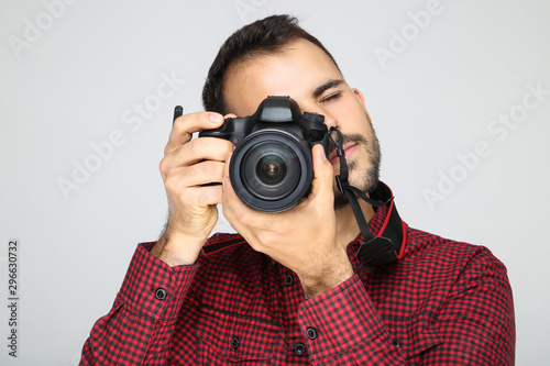 Young photographer with camera on grey background