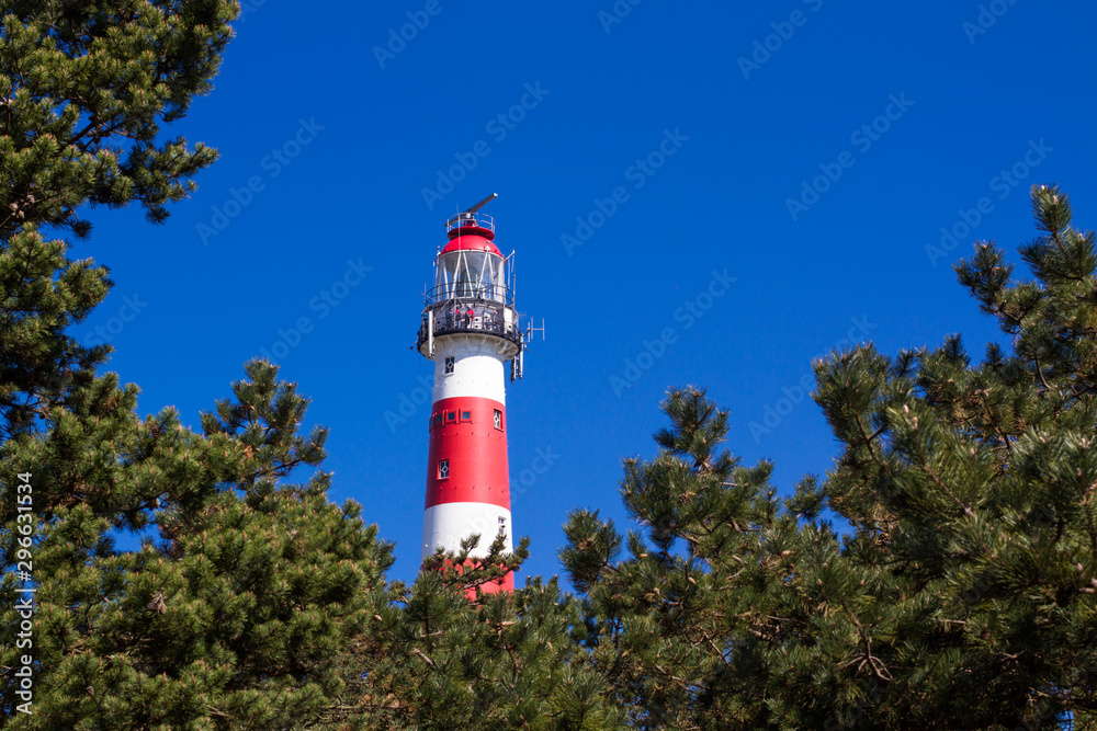 Vuurtoren, lighthouse of Ameland framed by green trees and blue sky in the background