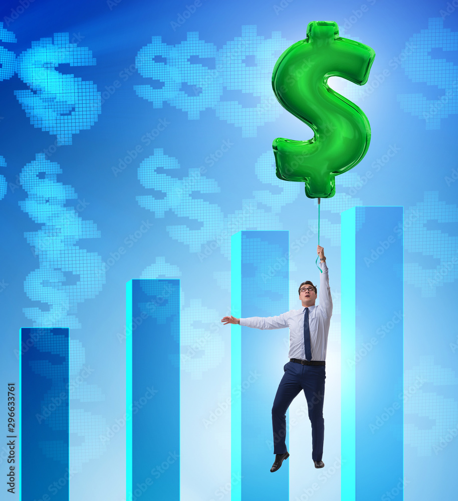 Businessman flying on dollar sign inflatable balloon over financ Businessman flying on dollar sign inflatable balloon over financ