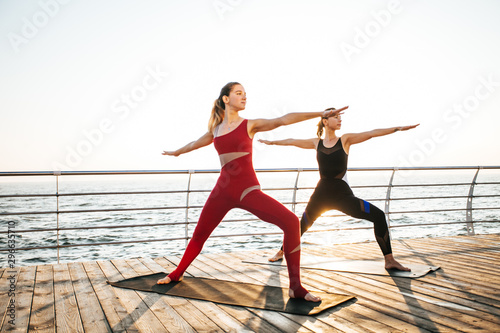 Young women practicing yoga on the seashore at dawn