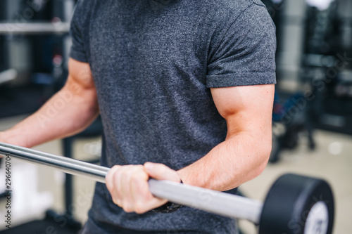 Sport, bodybuilding, lifestyle and people concept - young man lifting barbell and flexing muscles closeup. Strong man's hands at gym.