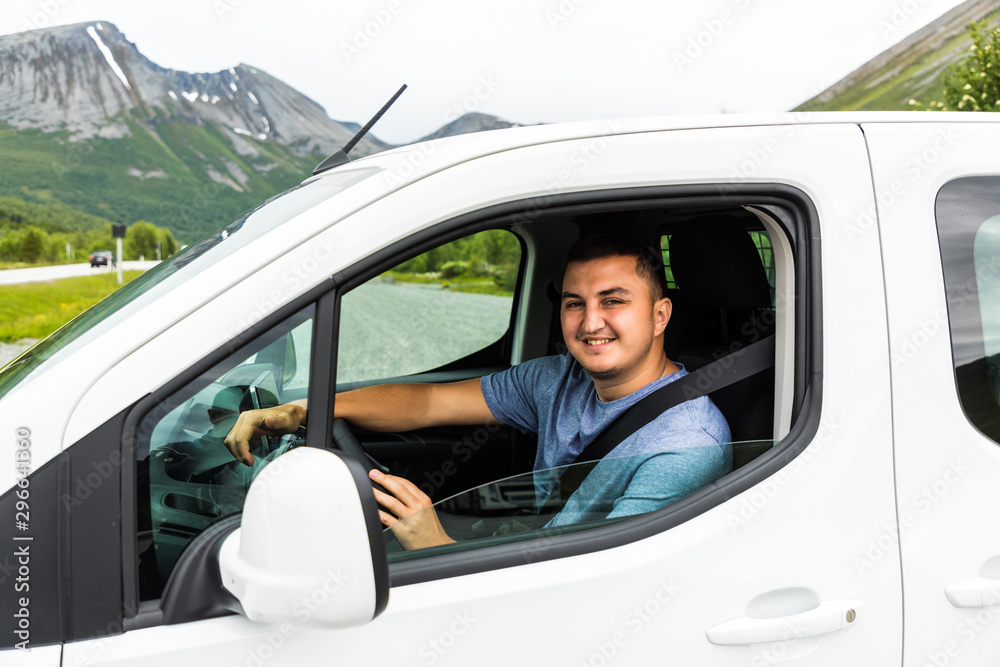 Handsome young man driving his car and smiling at camera Handsome young man driving his car and smiling at camera