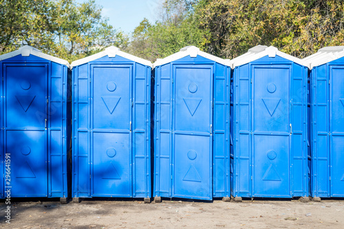 Long row of portable bio toilet cabins. Blue cabines of bio toilets. A large number of street toilets