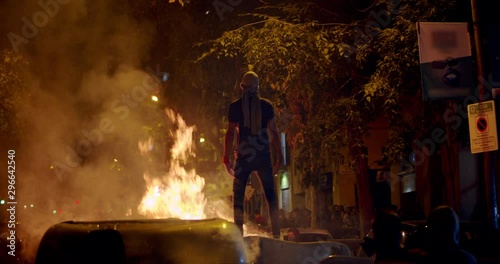 Young rebel riot revolutionary anarchist on barricade open arms during demonstration photo