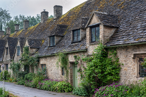 BIBURY, COTSWOLDS, UK - MAY 28, 2018: Traditional cotswold stone cottages built of distinctive yellow limestone in the world famous Arlington Row, Bibury, Gloucestershire, England    © LAURA