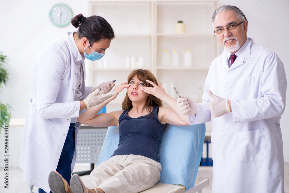 Two male doctors and young woman in plastic surgery concept Two male doctors and young woman in plastic surgery concept