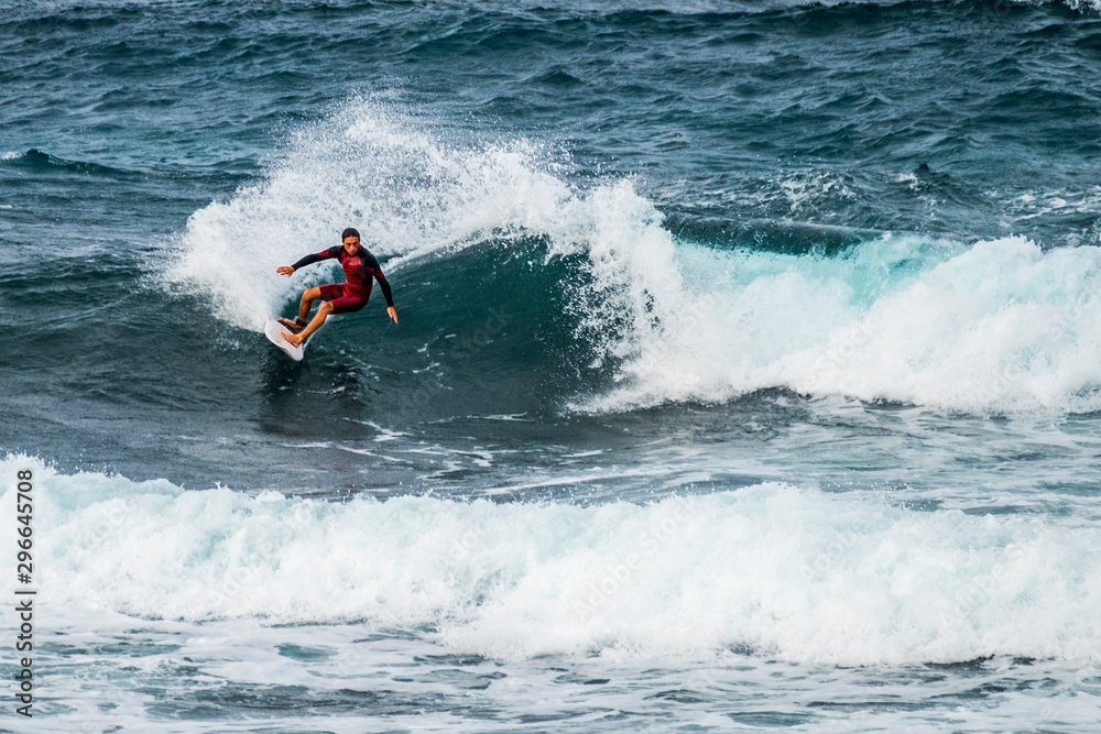 teenager surfing at the wave in tenerife playa de las americas - red wetsuits and beautiful and perfect wave - freestyle and doing tricks teenager surfing at the wave in tenerife playa de las americas - red wetsuits and beautiful and perfect wave - freestyle and doing tricks