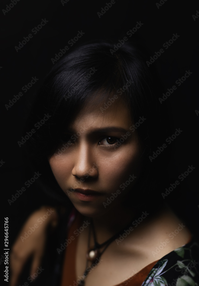 Asian short black haired woman Wearing jewelry made of leather and stone On her face, there is a small freckle On a black background and shadows Asian short black haired woman Wearing jewelry made of leather and stone On her face, there is a small freckle On a black background and shadows