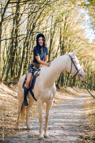 beautiful young girl riding a horse in the autumn forest