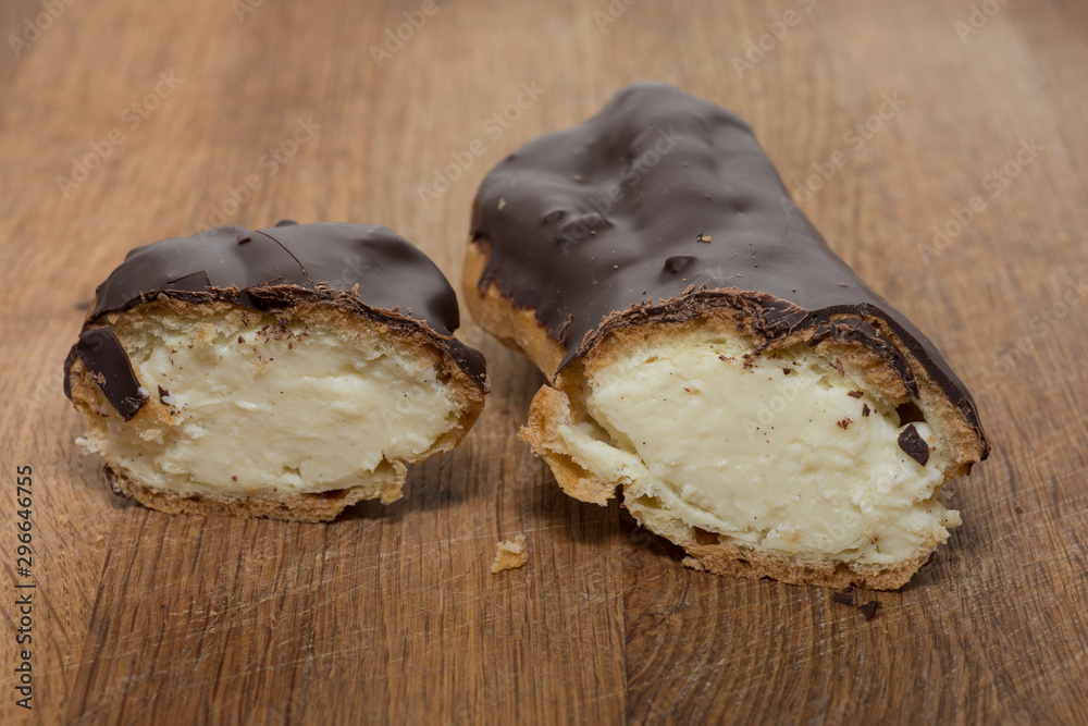 Close up of sliced chocolate eclair on brown wooden board Close up of sliced chocolate eclair on brown wooden board