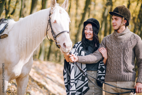 Beautiful young couple walking in the autumn forest. Horseback riding in the autumn forest.