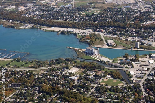 Fototapeta Naklejka Na Ścianę i Meble -  Looking down small plane at blue water of Georgian Bay and grain elevators  houses and streets at the mouth of the Owen Sound harbor
