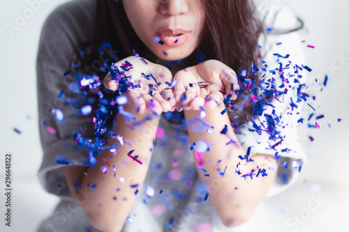 The woman who is blowing the glitter blue and fuchsia On a white background and bright light