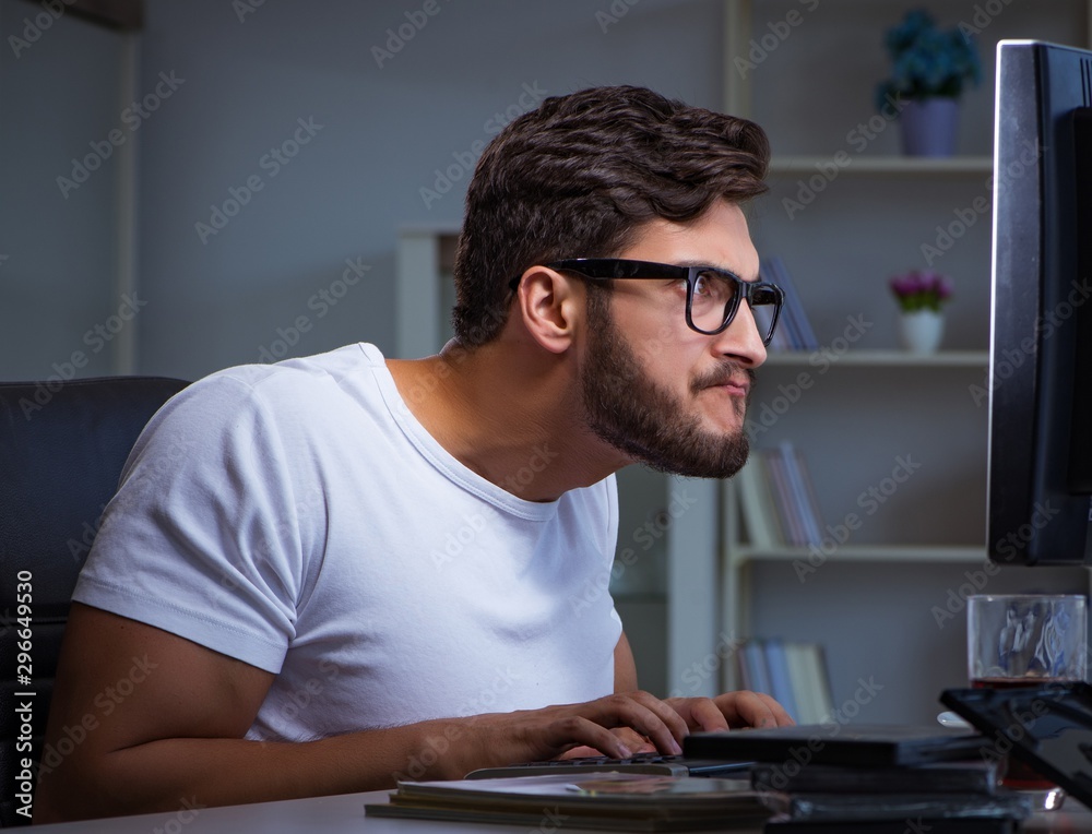 Young man staying late in office to do overtime work Young man staying late in office to do overtime work