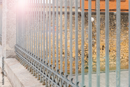 Gray metal fence with concrete columns on a stone wall background