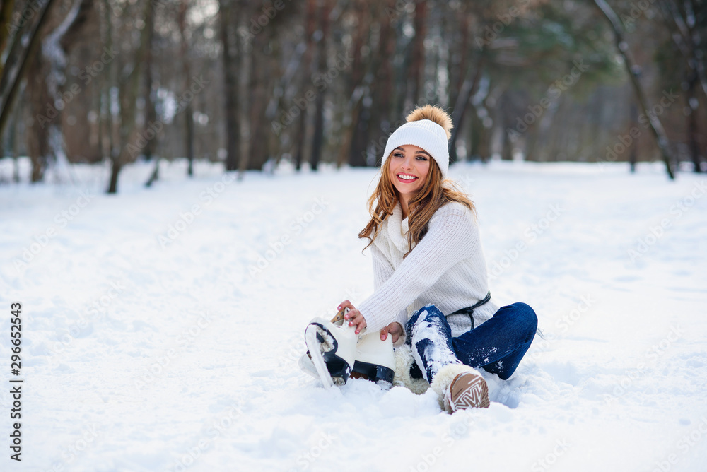 Beautiful happy woman weared in white sweater and hat with ice skates on the hands having fun in winter snowy park. Winter holidays concept. Beautiful happy woman weared in white sweater and hat with ice skates on the hands having fun in winter snowy park. Winter holidays concept.