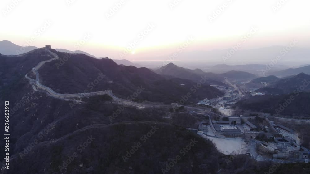 Aerial shot of Badaling section and gate, Great Wall of China at evening twilight. Camera move down. Dim colours at dusk, light stripe of stone fortification run up by hill side, small tower on top Aerial shot of Badaling section and gate, Great Wall of China at evening twilight. Camera move down. Dim colours at dusk, light stripe of stone fortification run up by hill side, small tower on top