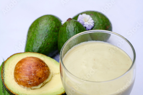 A Glass of Avocado Juice closed up, Healthy Smoothie with avocado fruit cut half on leaves on white background, Isolated.