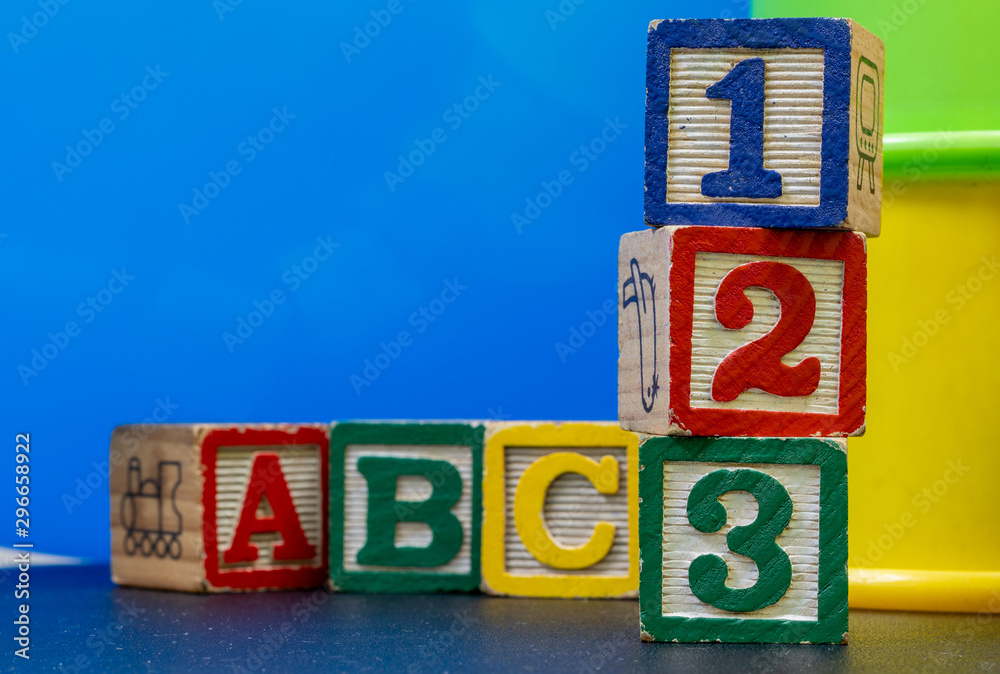 six wooden and colored play blocks, a,b,c, one, two, three. blue background. Learning beginnings concept six wooden and colored play blocks, a,b,c, one, two, three. blue background. Learning beginnings concept