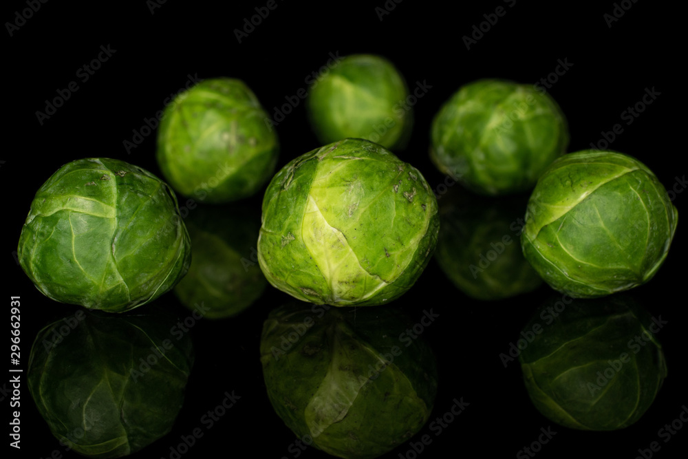 Group of six whole fresh green brussels sprout isolated on black glass Group of six whole fresh green brussels sprout isolated on black glass